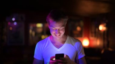 Kulüpte telefon kullanırken düşünerek mutlu yakışıklı delikanlı