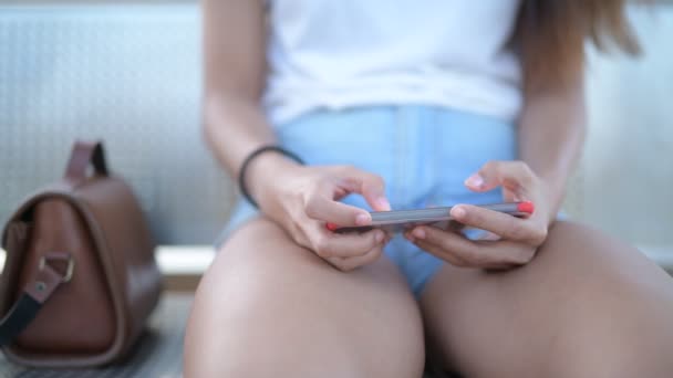 Mãos de mulher jovem usando telefone enquanto sentado — Vídeo de Stock