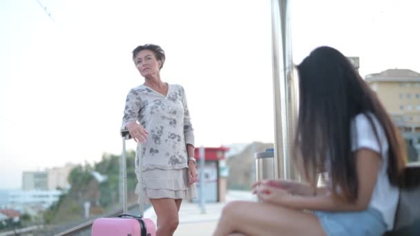 Зрелая туристка ждет на вокзале с молодой азиаткой — стоковое видео