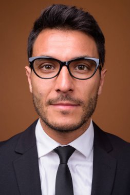 Genç yakışıklı İspanyol işadamı kahverengi zemin karşı takım elbise stüdyo çekim