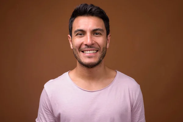 Joven hombre hispano guapo sonriendo sobre fondo marrón — Foto de Stock