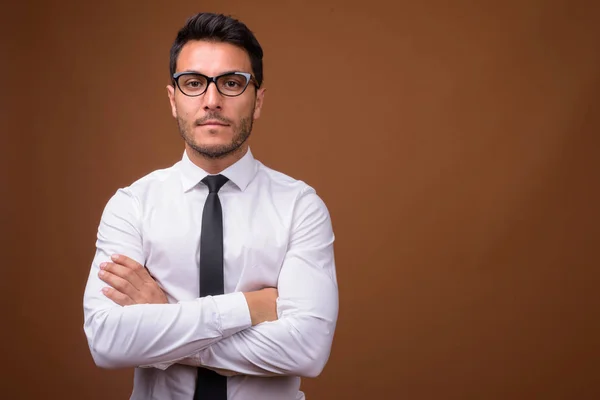 Young handsome Hispanic businessman against brown background — Stock Photo, Image