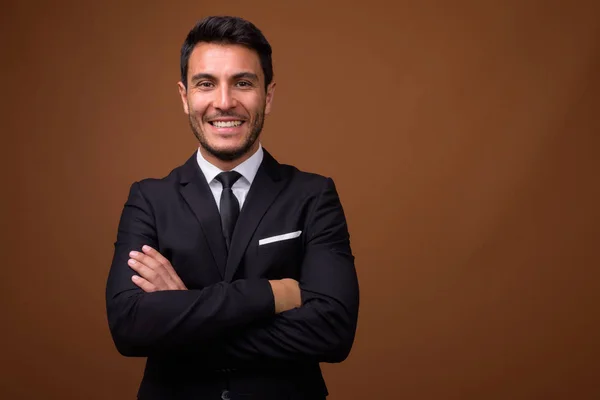 Junger gutaussehender hispanischer Geschäftsmann mit braunem Hintergrund — Stockfoto