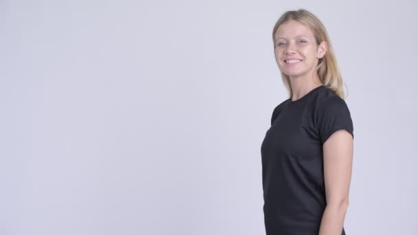 Profile view of young happy blonde woman looking at camera with arms crossed — Stock Video