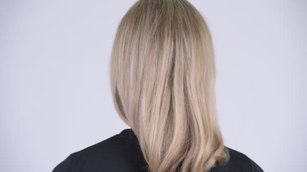 Вид сзади на молодую блондинку, оглядывающуюся назад — стоковое видео