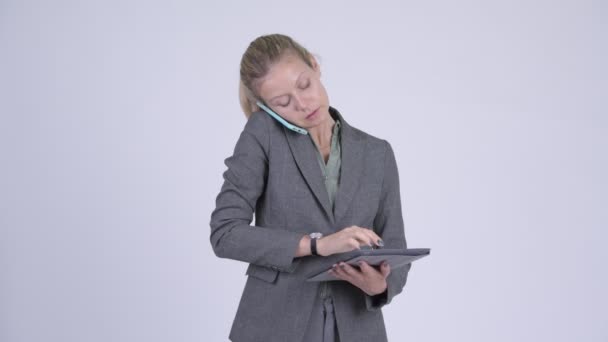 Jovem mulher de negócios loira feliz falando no telefone enquanto usa tablet digital — Vídeo de Stock