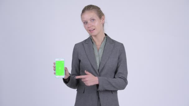 Unga glada blond affärskvinna visar telefonen och ger tummen upp — Stockvideo