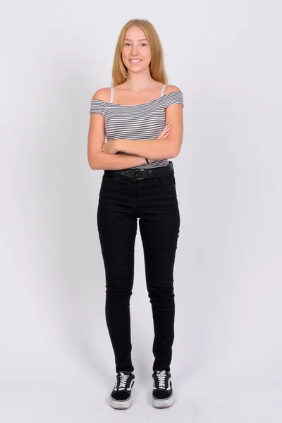 Full body shot of happy young beautiful blonde teenage girl smiling with arms crossed — Stock Photo, Image