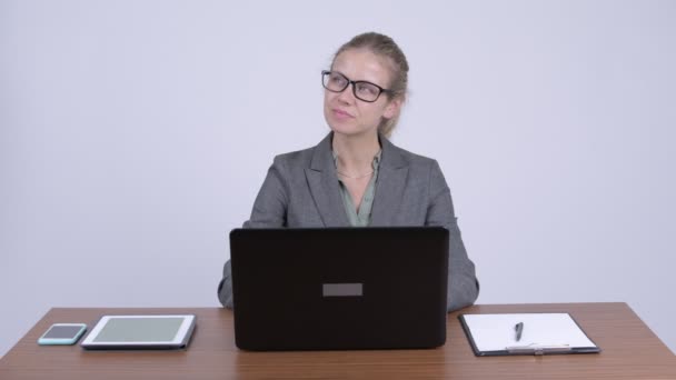 Молодая счастливая блондинка-бизнесмен думает, используя ноутбук на работе — стоковое видео