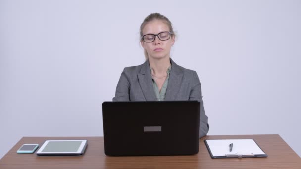 Νέοι όμορφη ξανθιά επιχειρηματίας νομίζοντας ενώ χρησιμοποιείτε φορητό υπολογιστή στην εργασία — Αρχείο Βίντεο