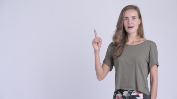 Glad ung vacker kvinna tänker samtidigt pekar uppåt — Stockvideo