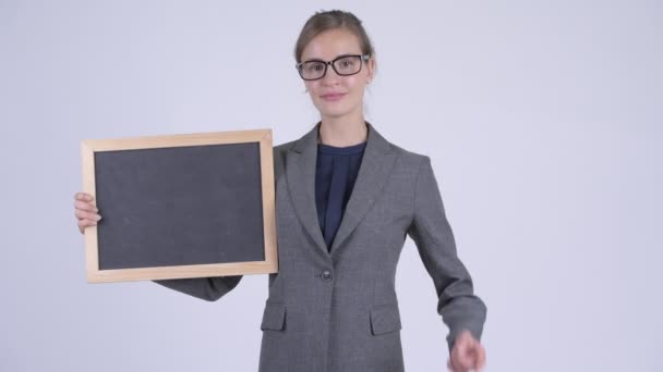 Unga glada affärskvinna ger tummen upp medan du håller blackboard — Stockvideo