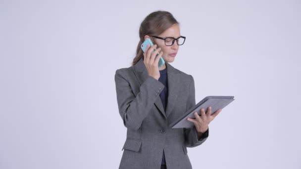 Молода щаслива бізнес-леді розмовляє по телефону і використовує цифровий планшет — стокове відео