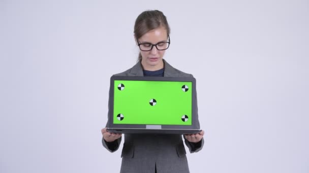 Junge glückliche Geschäftsfrau denkt beim Vorzeigen von Laptop — Stockvideo