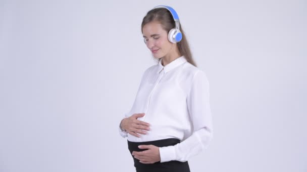 Young happy pregnant businesswoman listening to music — Stock Video