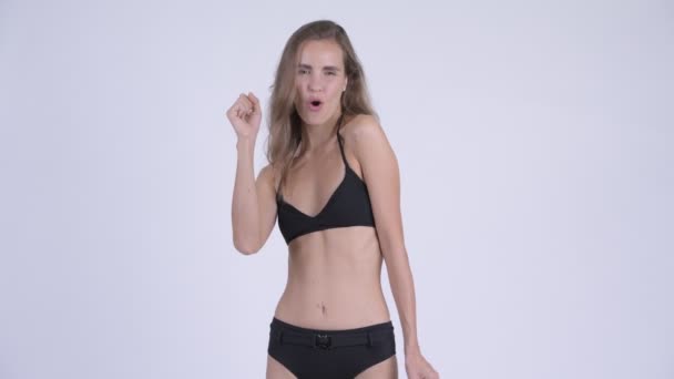 Glad ung vacker kvinna som bär bikini med nävar höjt — Stockvideo