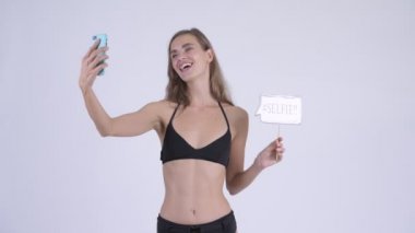Mutlu genç güzel kadın selfie kağıt işareti ile alarak bikini