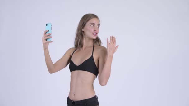 Feliz jovem mulher bonita em biquíni vídeo chamando e mostrando telefone — Vídeo de Stock