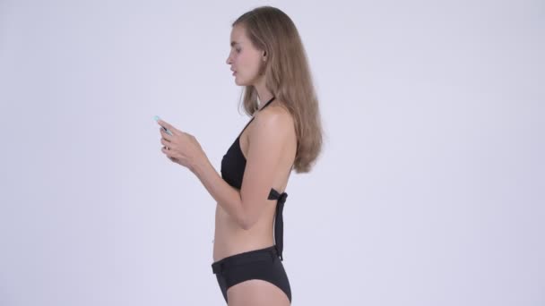 Fiatal nő a bikini, a telefon, hogy elvették a hossz-szelvény nézet — Stock videók