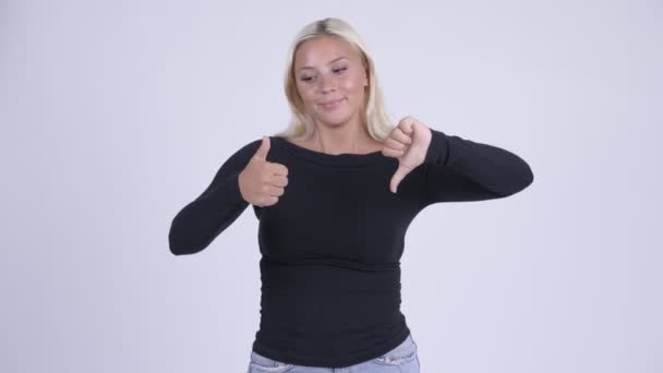 Ung förvirrad blond kvinna att välja mellan tummen upp och tummen ner — Stockvideo