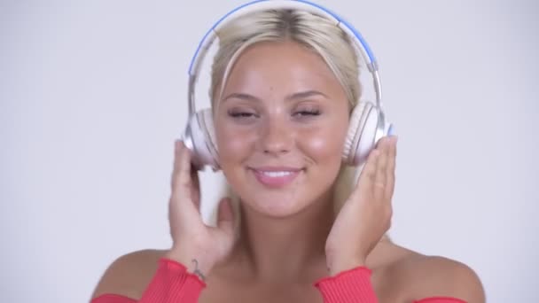 Cara de joven feliz hermosa mujer rubia escuchando música — Vídeo de stock