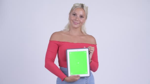 Χαρούμενος νεαρός όμορφη ξανθιά γυναίκα σκέψης ενώ δείχνει ψηφιακή δισκίο — Αρχείο Βίντεο
