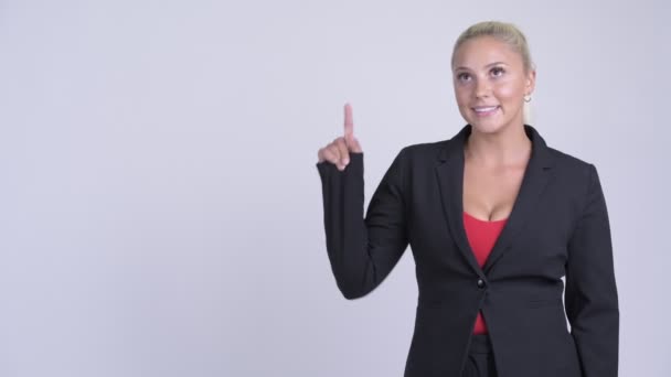 Joven mujer de negocios rubia feliz pensando y señalando hacia arriba — Vídeos de Stock