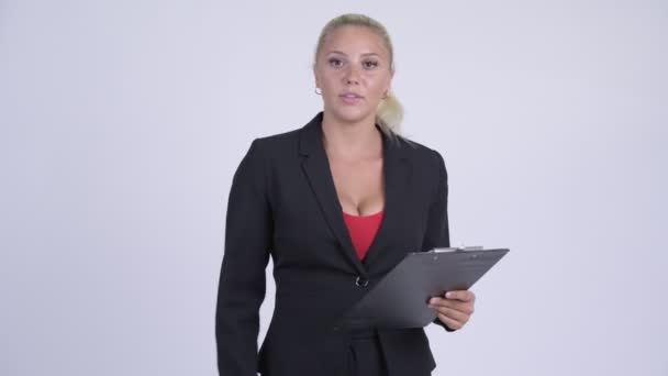 Young serious blonde businesswoman talking while reading on clipboard — Stock Video