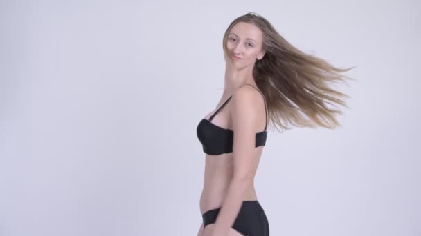 Vista posteriore della donna bionda felice in bikini che gira i capelli e guarda indietro — Video Stock