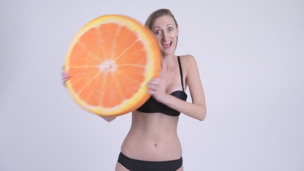 Glada blond kvinna i bikini hålla orange kudde som friska begrepp — Stockvideo