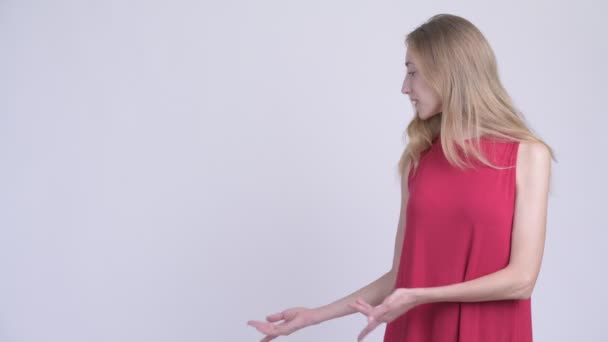 Щаслива молода красива блондинка показує щось на спину — стокове відео