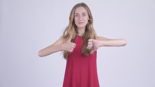 Young confused blonde woman choosing between thumbs up and thumbs down — Stock Video