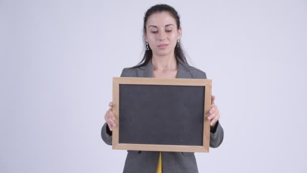 Jovem feliz bela empresária pensando enquanto segurando quadro negro — Vídeo de Stock