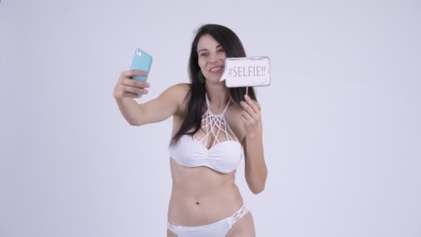 Glad ung vacker turist kvinna i bikini tar selfie med papper skylt — Stockvideo