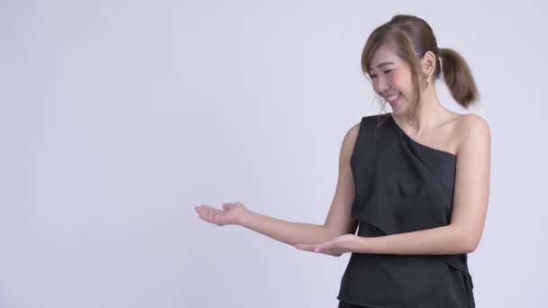 Ευτυχισμένος νεαρή όμορφη Ασιατική γυναίκα δείχνει κάτι στην πλάτη — Αρχείο Βίντεο