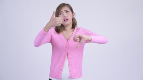 年轻的迷茫亚洲女人在竖起大拇指和大拇指之间做出选择 — 图库视频影像