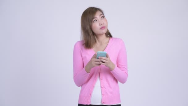 Jeune femme asiatique heureuse penser tout en utilisant le téléphone — Video