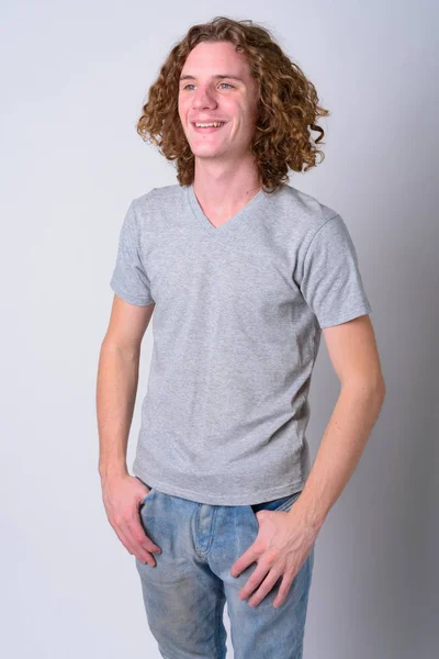 Retrato de jovem e bonito homem feliz com cabelo encaracolado pensando — Fotografia de Stock