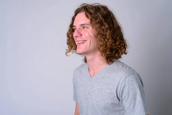 Rosto de jovem e bonito homem feliz com cabelo encaracolado pensando — Fotografia de Stock