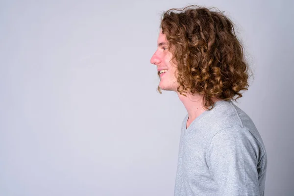 Visão de perfil de close-up de jovem homem bonito feliz com cabelo encaracolado sorrindo — Fotografia de Stock