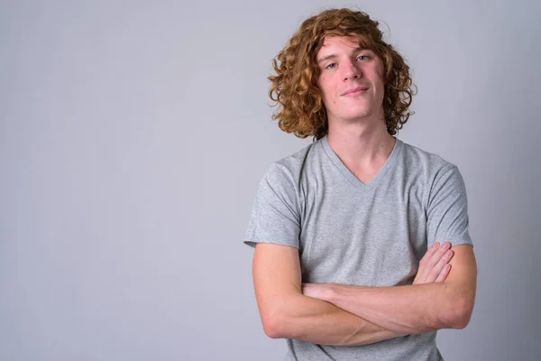 Retrato de homem bonito jovem com cabelos encaracolados cruzando braços — Fotografia de Stock