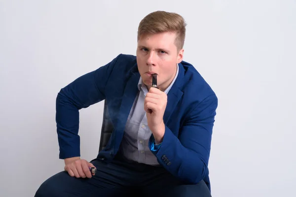 Joven guapo hombre de negocios rubia sentado mientras fuma pipa — Foto de Stock