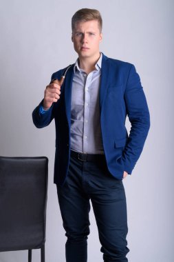 Genç yakışıklı sarışın işadamı yasaktır boru sandalye tutarken