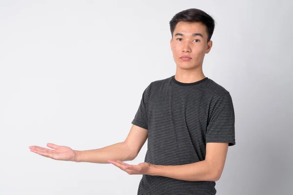 Porträt eines jungen hübschen asiatischen Mannes, der etwas zeigt — Stockfoto