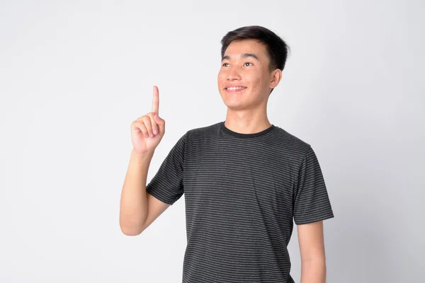 Retrato de joven feliz hombre asiático pensando y señalando hacia arriba — Foto de Stock