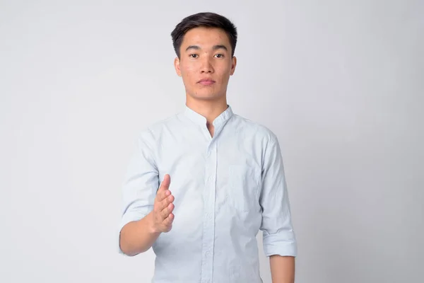 Porträt eines jungen hübschen asiatischen Geschäftsmannes beim Händedruck — Stockfoto