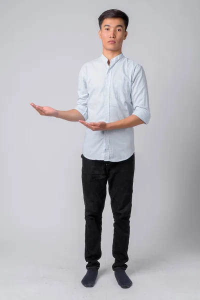 Full body shot of young handsome Asian businessman showing something — Stock Photo, Image