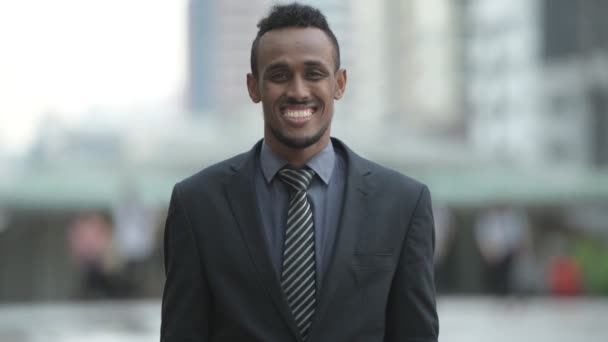 Feliz joven empresario africano sonriendo en las calles de la ciudad al aire libre — Vídeos de Stock