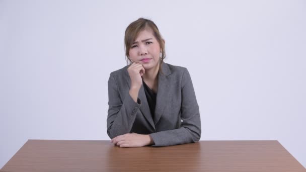 Joven feliz mujer de negocios asiática pensando y mirando hacia el escritorio — Vídeos de Stock
