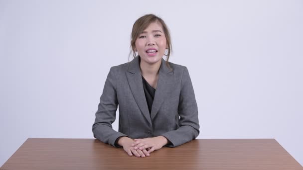 Junge glückliche asiatische Geschäftsfrau präsentiert etwas am Schreibtisch — Stockvideo
